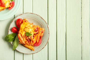 Yeşil ahşap zemin üzerinde domates soslu ve peynirli makarna tabakları