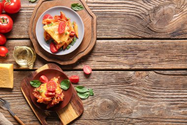 Ahşap zemin üzerinde domates soslu ve peynirli makarna tabakları.