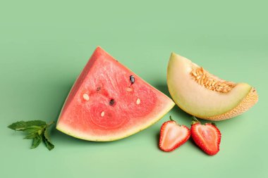 Bir parça taze karpuz ve yeşil arka planda farklı meyveler.