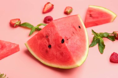 Taze karpuz parçaları ve pembe arka planda farklı meyveler.