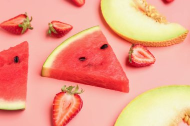 Taze karpuz parçaları ve pembe arka planda farklı meyveler.