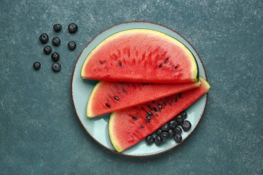 Mavi arka planda taze karpuz ve yaban mersini parçaları ile tabak