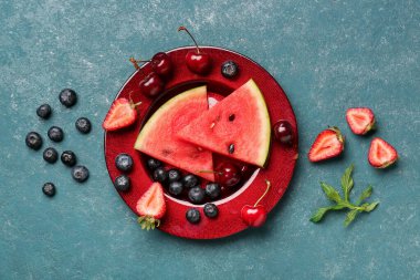 Taze karpuz parçaları ve mavi arka planda farklı böğürtlenler.
