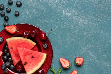 Taze karpuz parçaları ve mavi arka planda farklı böğürtlenler.