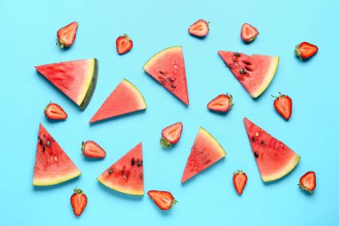 Taze karpuz parçaları ve mavi arka planda çilekler.