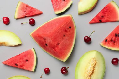 Taze karpuz parçaları ve gri arkaplanda farklı meyveler.