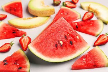 Taze karpuz parçaları ve gri arkaplanda farklı meyveler.