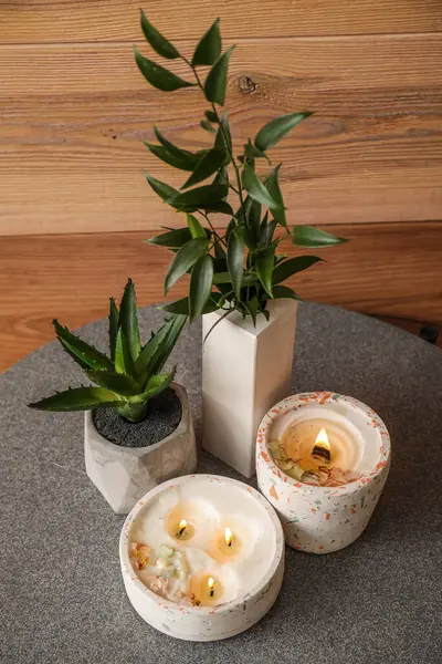 Zimmerpflanzen Und Brennende Kerzen Auf Dem Tisch Neben Der Holzwand — Stockfoto