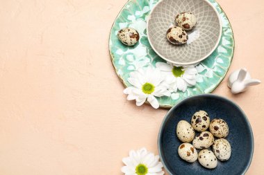 Composition with Easter quail eggs, chamomile flowers and bunny on beige background