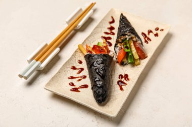 Soslu lezzetli suşi konileri ve hafif arka planda çubuklar.