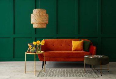 İçinde kahverengi kanepe, kahve masası ve yeşil duvarın yanında puf olan oturma odası.