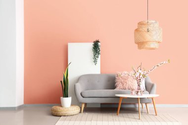 Gri kanepesi ve kahve masasında çiçek açan sakura dalları olan şık bir oturma odası.