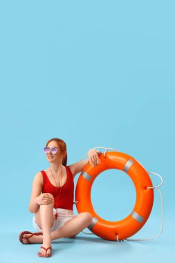 Mavi arka planda oturan yüzük şamandıralı kadın cankurtaran.