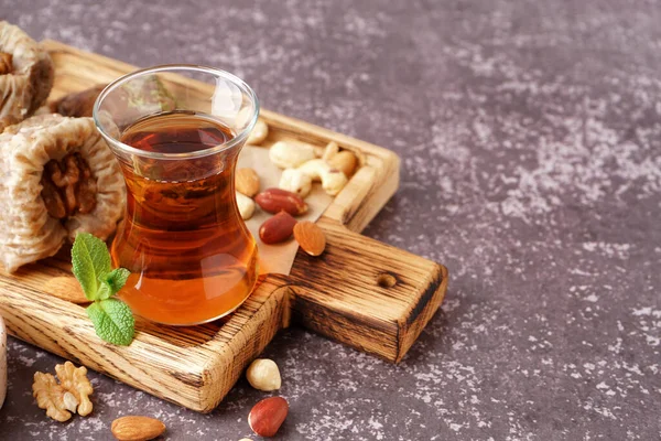 stock image Wooden board with glass of tea and Turkish delight on grey background