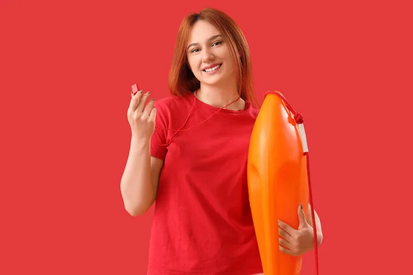 Female lifeguard with rescue buoy and whistle on red background