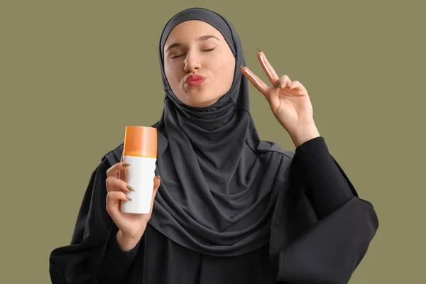 緑の背景に勝利ジェスチャーを示す日焼け止めクリームと若いイスラム教徒の女性 — ストック写真