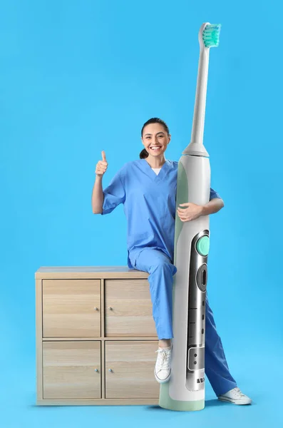 Zahnärztin Mit Großer Elektrischer Zahnbürste Daumen Hoch Auf Blauem Hintergrund — Stockfoto