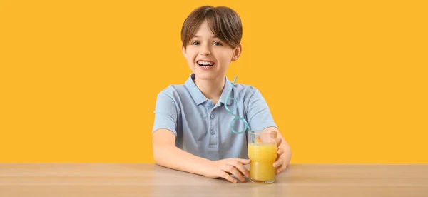 Kis Fiú Egy Pohár Gyümölcslével Asztalnál Narancssárga Háttér — Stock Fotó