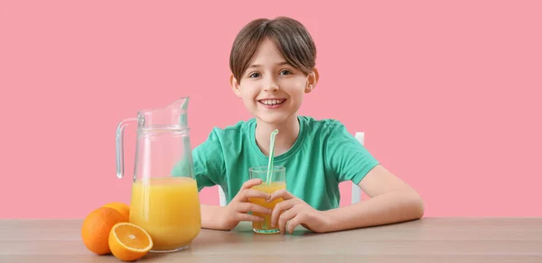 Kleiner Junge Mit Orangensaft Tisch Auf Rosa Hintergrund — Stockfoto
