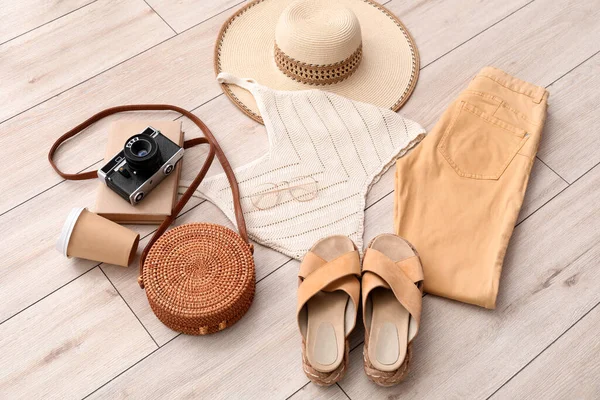 stock image Summer clothes with accessories, cup of coffee and photo camera on light wooden floor