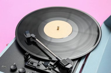 Pembe arka planda vinil diski olan kayıt çalar, yakın plan