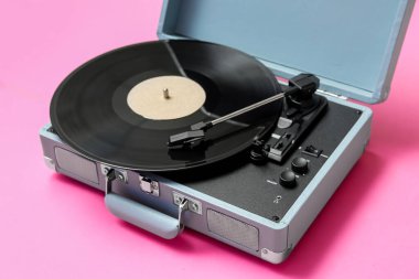 Pembe arka planda vinil diski olan kayıt çalar, yakın plan
