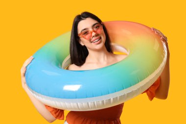 Turuncu arka planda şişme yüzüğü olan genç bir kadın.