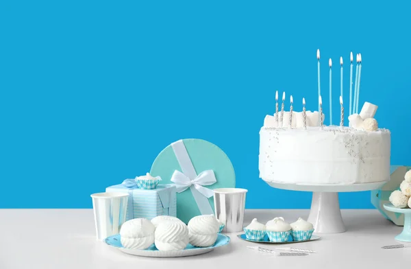 stock image Birthday cake with candles and sweets on white table near blue wall