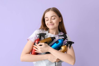 Leylak arka planında spreyleri ve kurutucusu olan bir kadın kuaför.