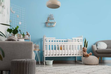 Bebek beşiği, kanepesi ve koltuğu olan şık bir yatak odası.