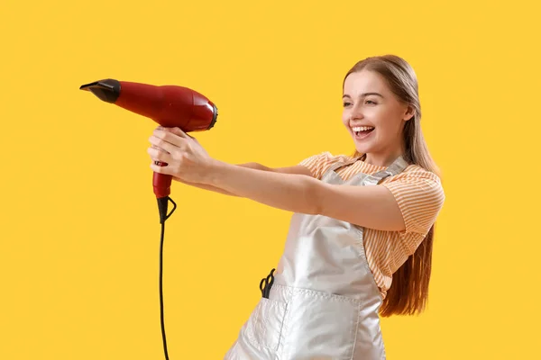 黄色の背景に乾燥機と女性の美容師 — ストック写真