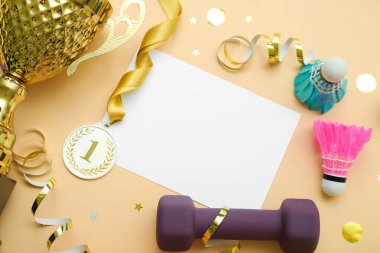 Altın bardaklı boş kart, bej arka planda birincilik madalyası ve spor ekipmanı