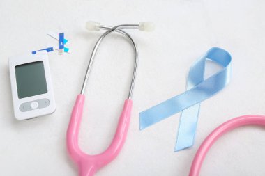 Beyaz arka planda glukometre ve steteskop ile farkındalık kurdelesi. Diyabet kavramı