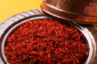 Turuncu arka planda safran yığını olan bir kase