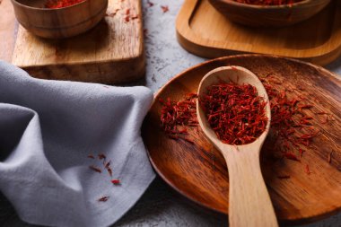 Gri arkaplanda safran yığını olan kase ve kaşık.