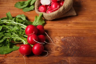 Ahşap arka planda yeşil yapraklı olgun turp sürüsü.