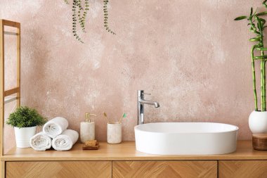 Masada bambu saplı lavabo, banyo aksesuarları ve vazo var.