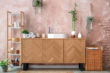 Lavabosu, çekmecesi ve raf ünitesi olan şık bir banyo.