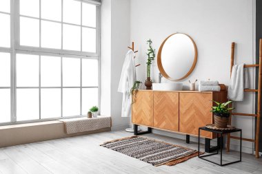 Interior of light bathroom with sink, drawers and mirror
