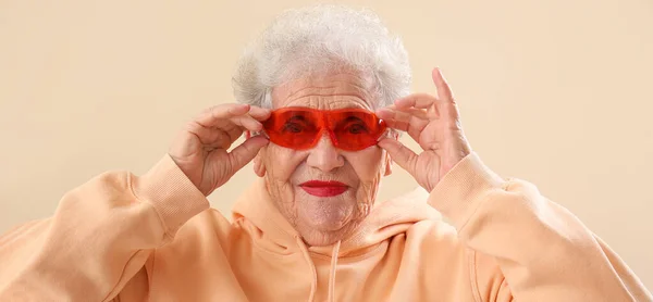 Κομψή Ηλικιωμένη Γυναίκα Γυαλιά Ηλίου Και Κουκούλα Μπεζ Φόντο — Φωτογραφία Αρχείου