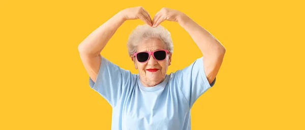 Ηλικιωμένη Γυναίκα Γυαλιά Ηλίου Που Κάνει Σχήμα Καρδιάς Χέρια Κίτρινο — Φωτογραφία Αρχείου