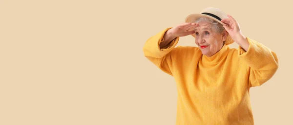 戴帽子的老年妇女望着远处米色的背景 有着文字的空间 — 图库照片