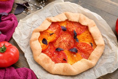 Lezzetli domates galeti ve ahşap arka planda fesleğen içeren kağıt fırını.