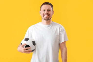 Sarı arka planda futbol topu olan mutlu adam.
