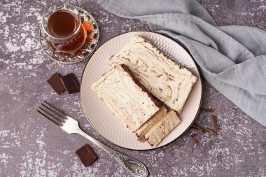Lezzetli mermer helva ve arkaplanda Türk çayı olan cam parçaları.