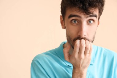 Genç adam bej arka planda panik atak geçiriyor.