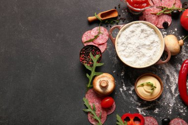 Koyu arkaplanda pizza hazırlamak için farklı malzemeler.