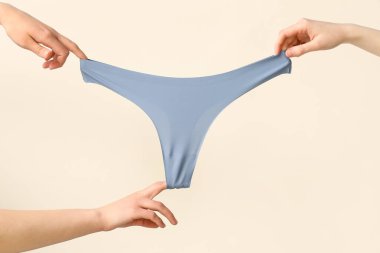 Hafif arka planda şık külotlu kadın elleri, yakın plan.