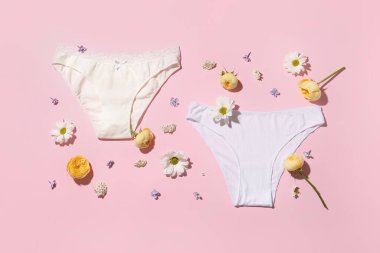 Şık kadın külotları ve pembe arka planda güzel çiçekleri olan kompozisyon