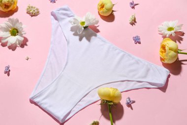 Şık kadın külotları ve pembe arka planda güzel çiçekleri olan kompozisyon, yakın plan.